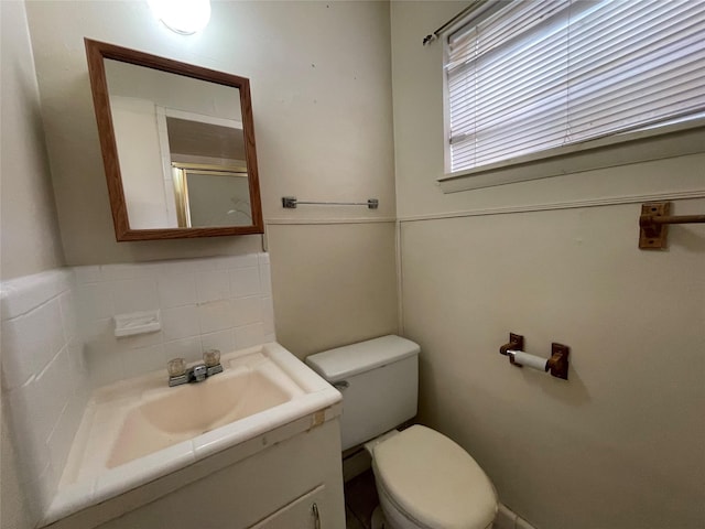 bathroom with a shower with shower door, decorative backsplash, toilet, and vanity