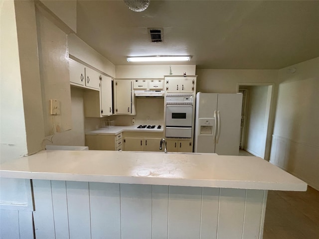 kitchen featuring white appliances, visible vents, a peninsula, under cabinet range hood, and a warming drawer