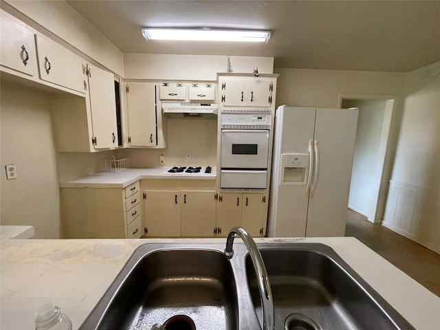 kitchen featuring white appliances, a sink, light countertops, under cabinet range hood, and a warming drawer