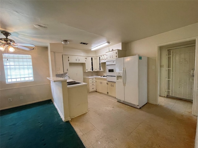 kitchen featuring a sink, white refrigerator with ice dispenser, a peninsula, light countertops, and ceiling fan