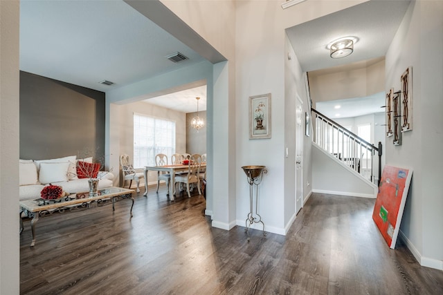 foyer entrance with visible vents, stairs, baseboards, and dark wood-style flooring