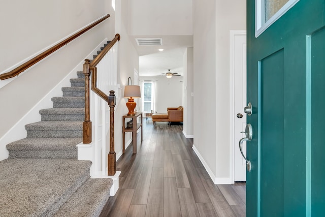 entryway featuring visible vents, baseboards, stairs, dark wood-style floors, and a ceiling fan