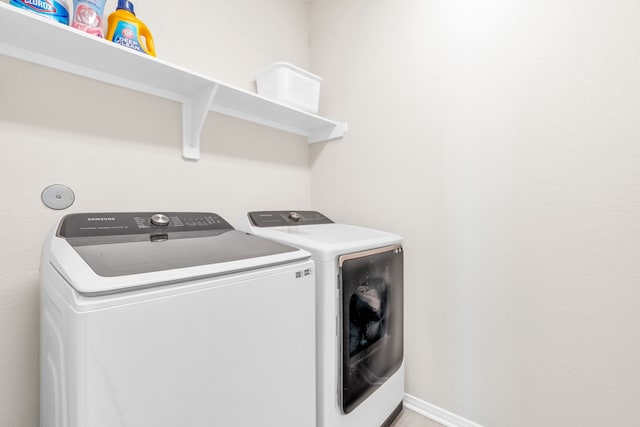 washroom with laundry area, baseboards, and washing machine and clothes dryer