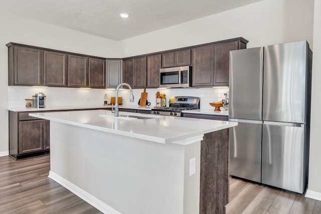 kitchen featuring light countertops, light wood-style flooring, dark brown cabinets, and appliances with stainless steel finishes