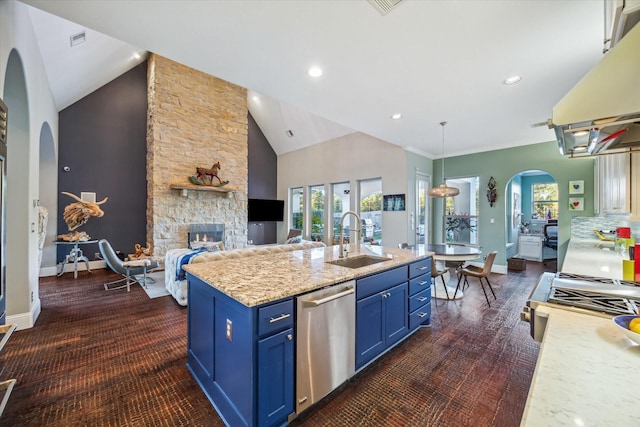 kitchen featuring a sink, blue cabinetry, under cabinet range hood, stainless steel dishwasher, and a stone fireplace