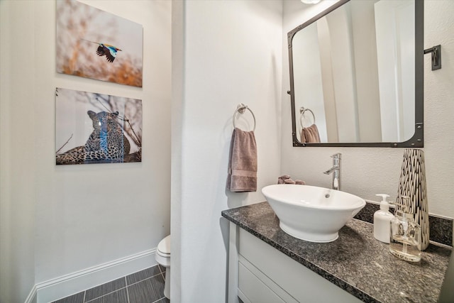 bathroom featuring baseboards, toilet, and vanity