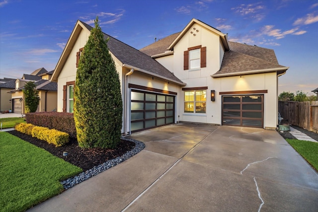 view of front of property with fence, concrete driveway, roof with shingles, stucco siding, and an attached garage