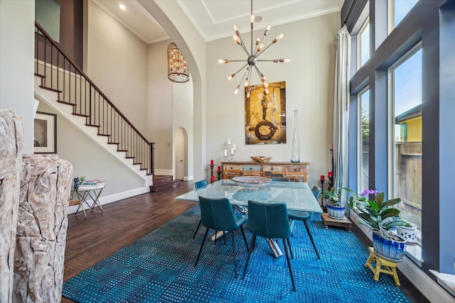 dining area with wood finished floors, arched walkways, crown molding, baseboards, and a chandelier