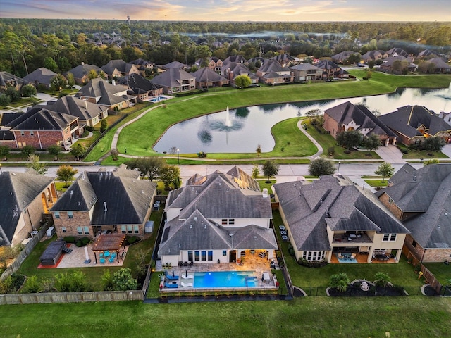 aerial view at dusk featuring a residential view and a water view