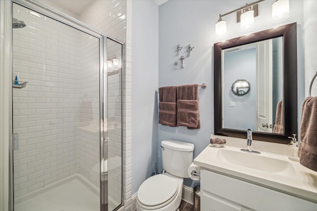 bathroom with baseboards, vanity, a shower stall, and toilet