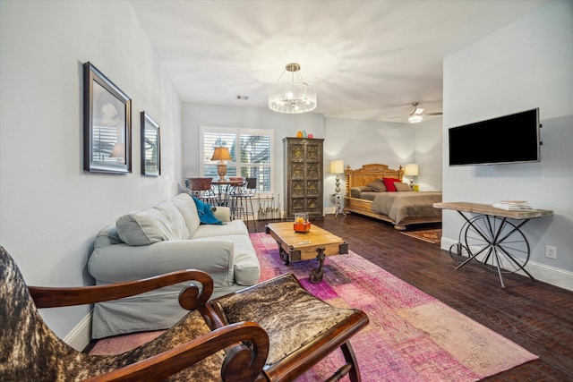 living room with visible vents, ceiling fan with notable chandelier, baseboards, and wood finished floors