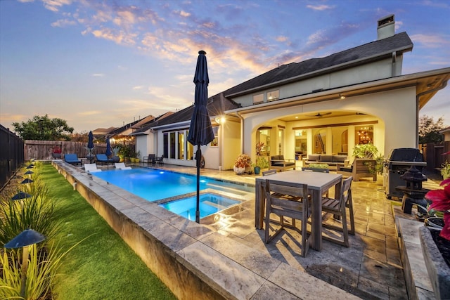 pool at dusk with outdoor lounge area, a patio area, and a fenced backyard