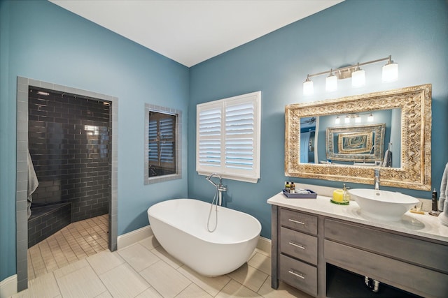 bathroom featuring tile patterned floors, a tile shower, baseboards, a soaking tub, and vanity