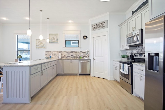 kitchen with light stone counters, a peninsula, stainless steel appliances, light wood-style floors, and crown molding