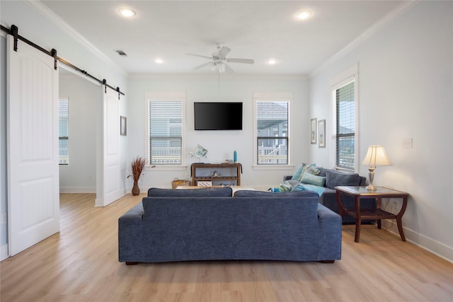 living area with light wood-style floors, visible vents, crown molding, and a barn door