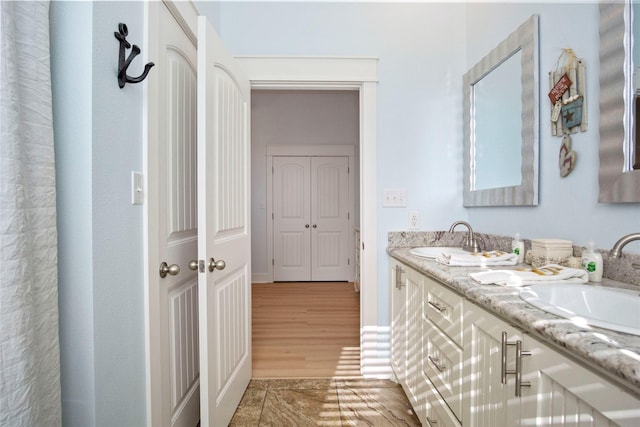 full bathroom featuring double vanity, wood finished floors, and a sink