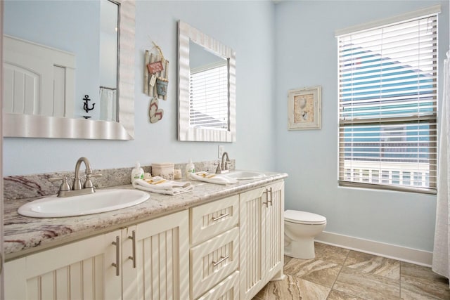 full bathroom with a sink, baseboards, toilet, and double vanity