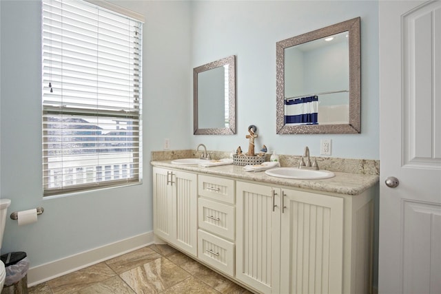 bathroom with a sink, baseboards, and double vanity