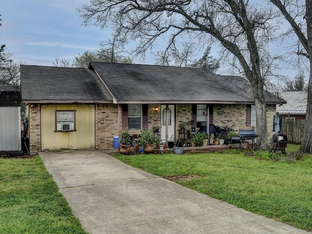 ranch-style house with brick siding, a porch, a front yard, roof with shingles, and cooling unit