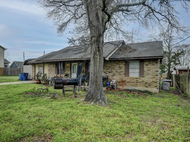 rear view of property with a yard, brick siding, and fence