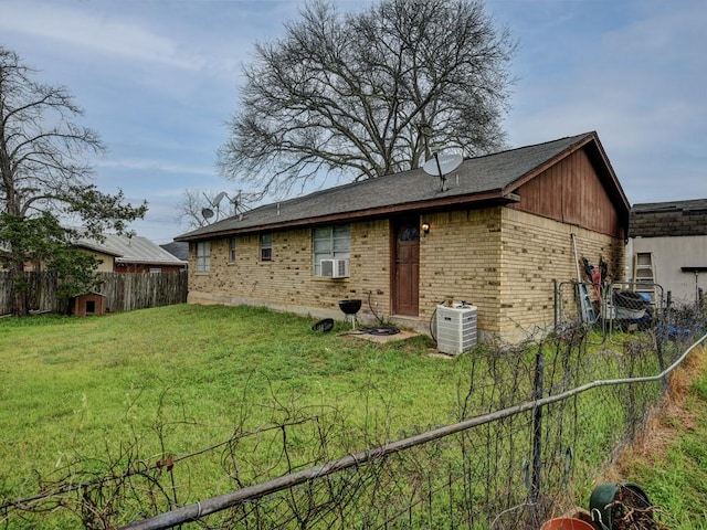 rear view of property with brick siding, a yard, and fence