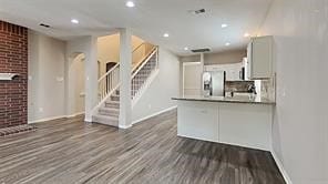 kitchen featuring stainless steel refrigerator with ice dispenser, recessed lighting, a peninsula, brick wall, and dark wood-style flooring