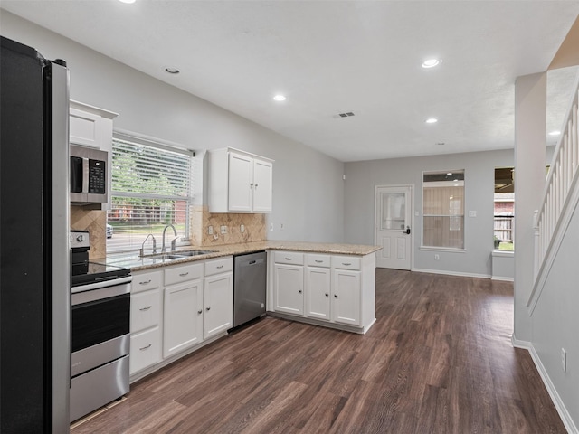 23134 Beech Canyon Dr, Katy, TX 77494 - kitchen featuring appliances with stainless steel finishes, a sink, a peninsula, dark wood-type flooring, and white cabinetry