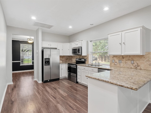 23134 Beech Canyon Dr, Katy, TX 77494 - kitchen featuring stainless steel appliances, a peninsula, dark wood-style floors, white cabinetry, and recessed lighting