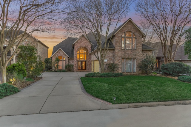 view of front of home with a front lawn, concrete driveway, a shingled roof, a garage, and brick siding