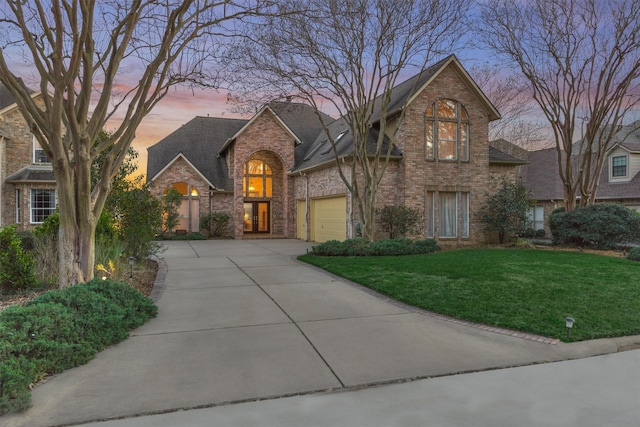 traditional home with a garage, concrete driveway, a yard, and brick siding