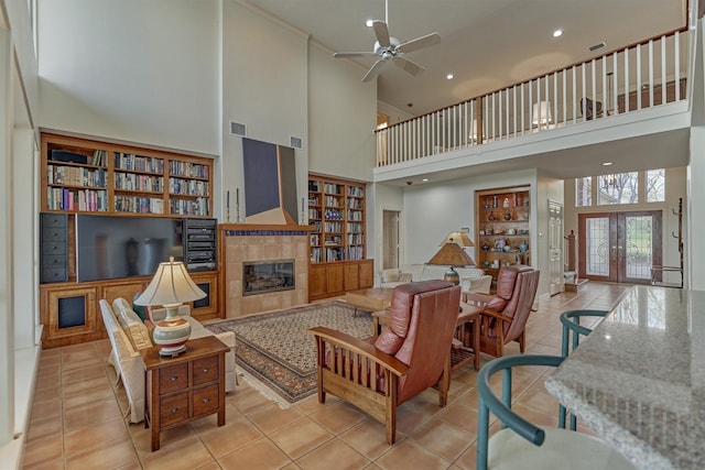 tiled living area featuring visible vents, ceiling fan, built in features, french doors, and a fireplace