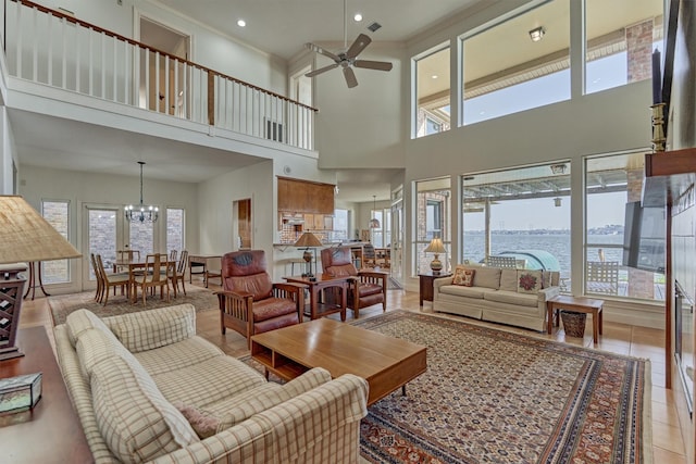 tiled living area with ceiling fan with notable chandelier, crown molding, recessed lighting, and a healthy amount of sunlight