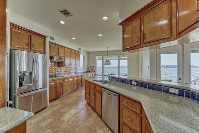 kitchen with visible vents, brown cabinets, under cabinet range hood, a sink, and stainless steel appliances