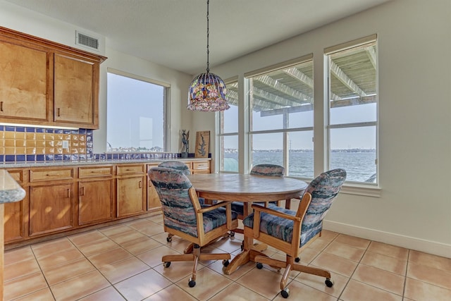 dining room with light tile patterned flooring, baseboards, visible vents, and plenty of natural light