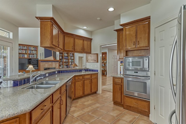 84 Waterford Way, Montgomery, TX 77356 - kitchen with appliances with stainless steel finishes, a sink, brown cabinets, light tile patterned floors, and recessed lighting