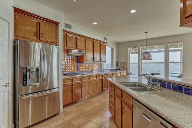 kitchen with visible vents, a sink, under cabinet range hood, appliances with stainless steel finishes, and brown cabinets