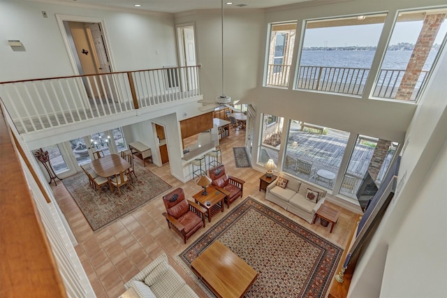 living room with ceiling fan, a towering ceiling, and a water view