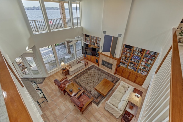 living area with visible vents, a fireplace, tile patterned flooring, a water view, and a towering ceiling