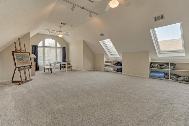 bonus room with light carpet, visible vents, vaulted ceiling with skylight, and a ceiling fan