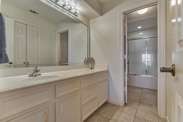 full bath with vanity, visible vents, shower / bath combination with glass door, tile patterned floors, and toilet