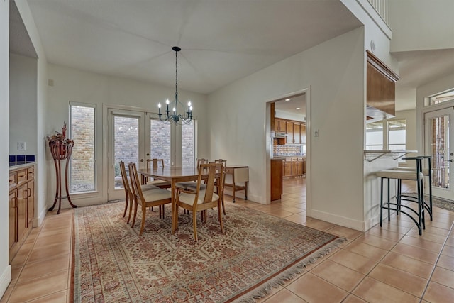 dining space with light tile patterned flooring, french doors, baseboards, and a chandelier