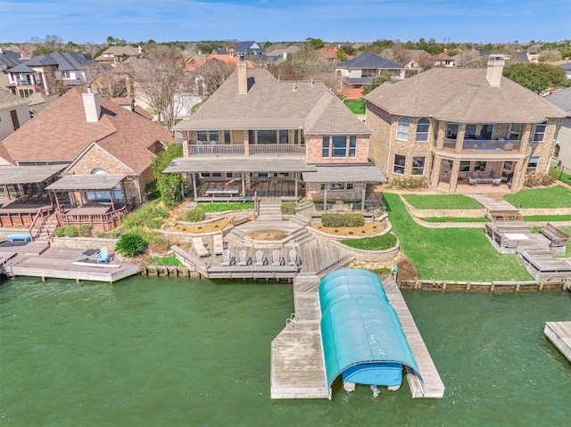 rear view of property with a residential view, a chimney, a balcony, and a water view