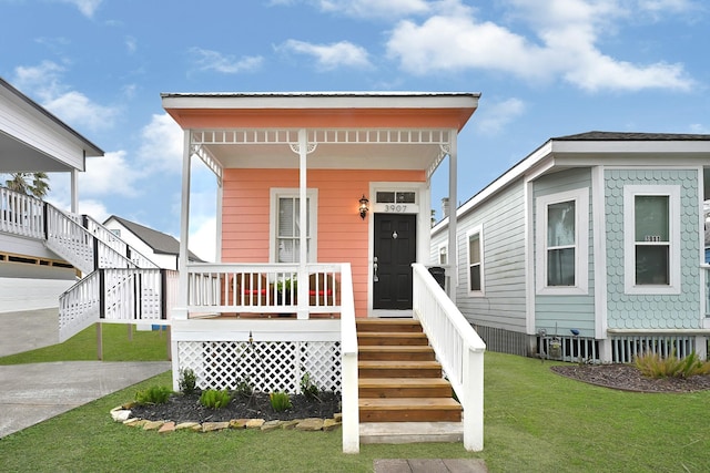 view of front facade featuring covered porch, concrete driveway, stairs, and a front yard