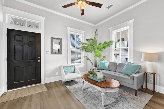 living room with visible vents, baseboards, wood finished floors, and ornamental molding