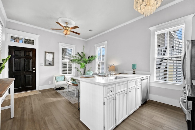 kitchen featuring wood finished floors, white cabinetry, a peninsula, a sink, and stainless steel dishwasher