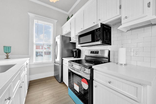 kitchen featuring tasteful backsplash, light wood finished floors, crown molding, white cabinets, and stainless steel appliances