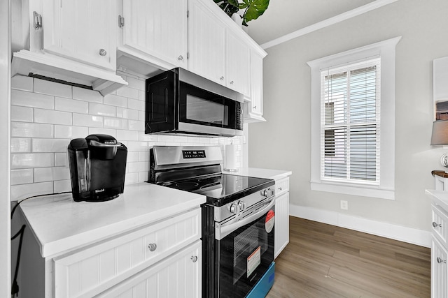 kitchen featuring light wood finished floors, ornamental molding, stainless steel appliances, light countertops, and tasteful backsplash