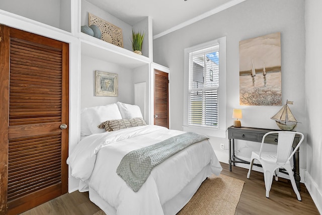 bedroom with wood finished floors and ornamental molding