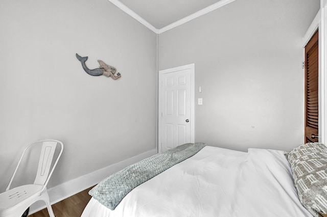 bedroom with a closet, dark wood-type flooring, baseboards, and ornamental molding