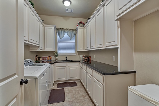 washroom featuring a sink, visible vents, cabinet space, and independent washer and dryer